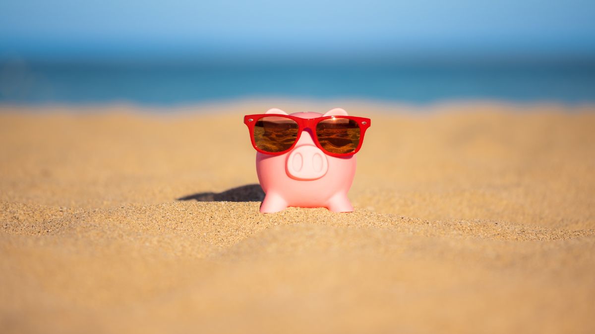 A piggy bank at the beach wearing sunglasses