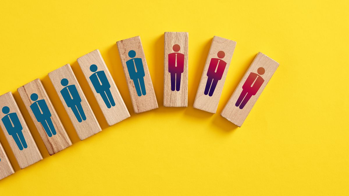 Wooden blocks that have worker graphics on them. Some are blue and and some are red to indicated laid off employees.
